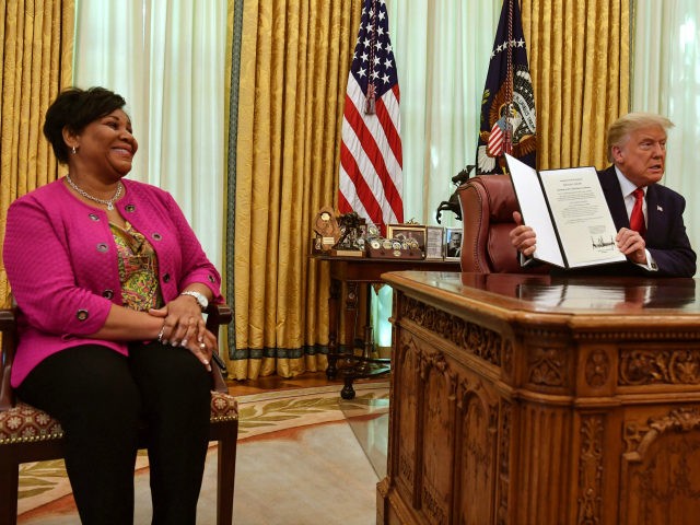 US President Donald Trump displays Alice Johnson's full pardon in the Oval Office of the White House in Washington, DC, on August 28, 2020. - Trump granted Johnson, a criminal justice reform advocate and former federal prisoner, a full pardon after commuting her sentence in 2018. (Photo by NICHOLAS KAMM …