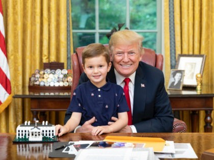Donald Trump holds his grandson Joseph in the Oval Office, where a White House replica Joseph constructed with Legos sits on the desk.