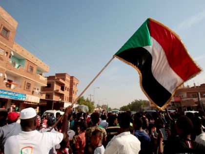 A man waves a Sudanese flag as Sudanese protesters demonstrate in Khartoum on July 25, 2019. - Sudanese protest leaders and their rebel partners have ended their differences over a power-sharing deal signed with the country's military rulers, vowing to work jointly for peace, a leading protest group said on …