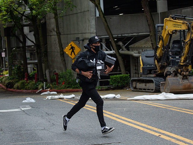 BELLEVUE, WA - MAY 31: A person runs from Bellevue Square Mall while carrying items on May 31, 2020 in Bellevue, Washington. Protests due to the recent death of George Floyd took place in Bellevue in addition to Seattle, with looting in Bellevue and at least one burned automobile there. …