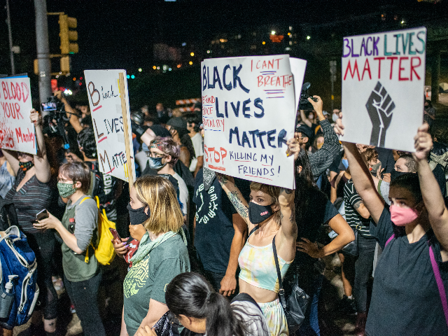 People hold up signs in front of the Austin Police Department after a vigil for Garrett Foster on July 26, 2020 in downtown Austin, Texas.  Garrett Foster, 28, who was armed and attending a Black Lives Matter protest, was shot dead after a chaotic altercation with a motorist who allegedly drove into the crowd.  The unknown suspect was arrested.  (Photo by Sergio Flores/Getty Images)