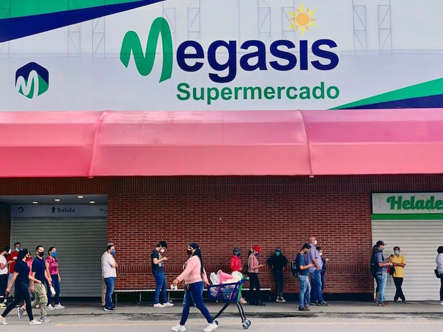 People wear face masks as a preventive measure against the spread of the novel coronavirus, COVID-19, as people queue outside "Megasis," the first Iranian supermarket in Venezuela, in Caracas on July 31, 2020. - The relationship between Tehran and Caracas is growing, challenging their common enemy, the United States. First, …