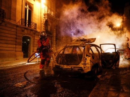 TOPSHOT - Firefighters extinguish a burning car near the Champs-Elysees in Paris on August