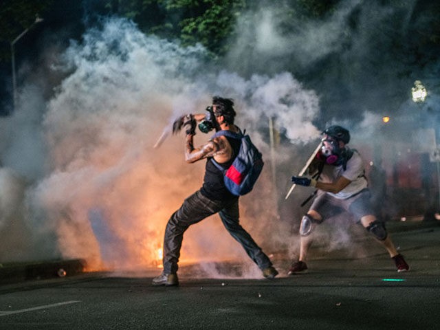 KENOSHA, WI - AUGUST 24: Demonstrators throw tear gas back at law enforcement on August 24, 2020 in Kenosha, Wisconsin. Additional law enforcement were deployed to protect the courthouse. Civil unrest occurred after the shooting of Jacob Blake, 29, on August 23. Blake was shot multiple times in the back …