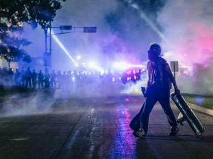 A demonstrator carries a make-shift shield across the street on August 25, 2020 in Kenosha, Wisconsin. As the city declared a state of emergency curfew, a third night of civil unrest occurred after the shooting of Jacob Blake, 29, on August 23. Video shot of the incident appears to show …