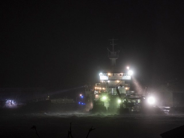 A picture taken on August 27, 2020 shows a ship anchored to a dock using a searchlight to