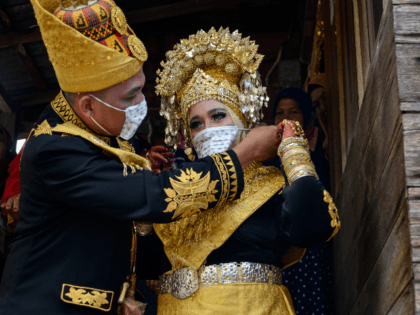 A newly-wedded couple put on face masks during a traditional wedding at a village in Lhoknga, Aceh province on August 30, 2020. (Photo by CHAIDEER MAHYUDDIN / AFP) (Photo by CHAIDEER MAHYUDDIN/AFP via Getty Images)