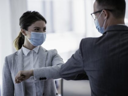 Businessman and businesswoman with medical mask in office.