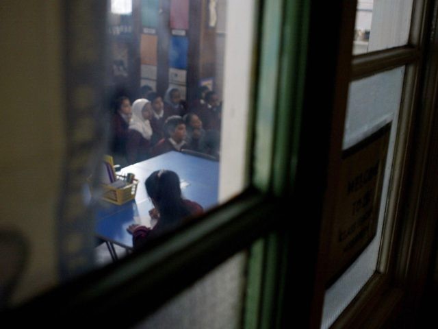 LONDON, UNITED KINGDOM: WITH "RELIGIOUS EDUCATION A FESTIVAL OF LIGHT IN BRITAIN" A young girl wearing a muslim headscarf listens to her teachers leason while in class at Featherstone Primary school 09 December2003 in Southall London. . Sitting cross-legged the children intone a Sikh chant accompanied by Punjabi instruments as …