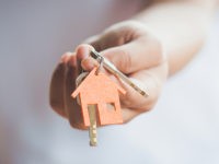 Female hand holding keys with house key,real estate agent.