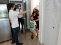 Sixteen-year-old Steven Ferreiro, left, founder of the local non-profit Helping Others and Giving Hope, hands over keys to a new apartment to Ayleen Apathy, right, as her son Vaughn, 7, second from right, and Alex Ballina, second from left, director of asset management for AHS Residential real estate development company, …