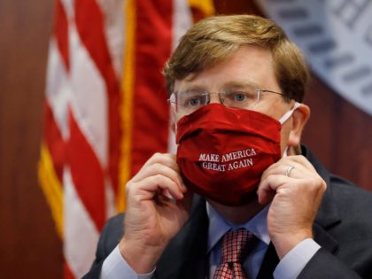 Mississippi Gov. Tate Reeves adjusts his "Make America Great Again," face mask upon conclu