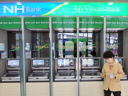 A South Korean woman looks at her bankbook in front of automated-teller machines of the Na