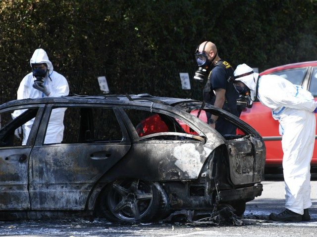 Police forensic officers inspect a burnedßout car near the scene where a woman was shot d