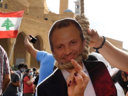A woman gives the finger to a cardboard cut-out of former Foreign Minister Gibran Bassil h