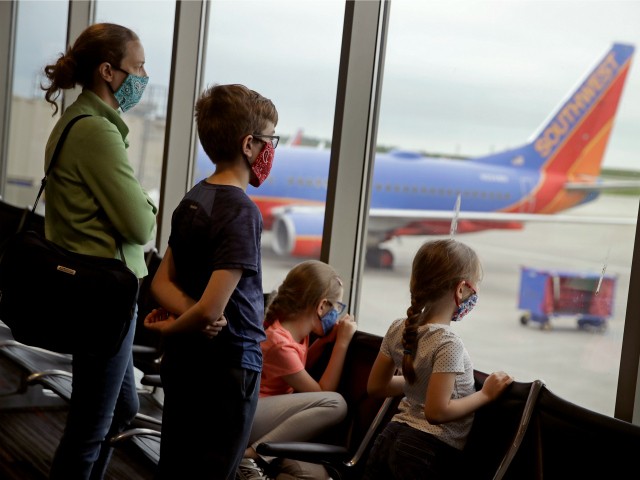 A family wearing masks waits to board a Southwest Airlines flight Sunday, May 24, 2020 at Kansas City International airport in Kansas City, Mo. About three dozen passengers boarded the plane with a capacity of nearly 150 as people are opting not to travel on the normally busy Memorial Day holiday to minimize the chance of spreading COVID-19 coronavirus. (AP Photo/Charlie Riedel)