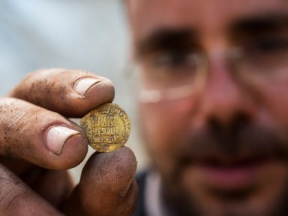 Israeli archaeologist Shahar Krispin displays a gold coin that was discovered at an archeo