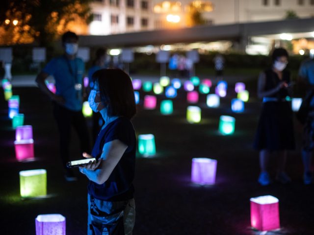 A visitor watches a screen (not pictured) displaying virtual lanterns as paper lanterns ar