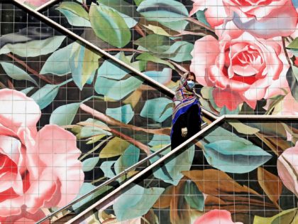 An Iranian woman wearing a protective mask due to the COVID-19 pandemic, climbs up a decor