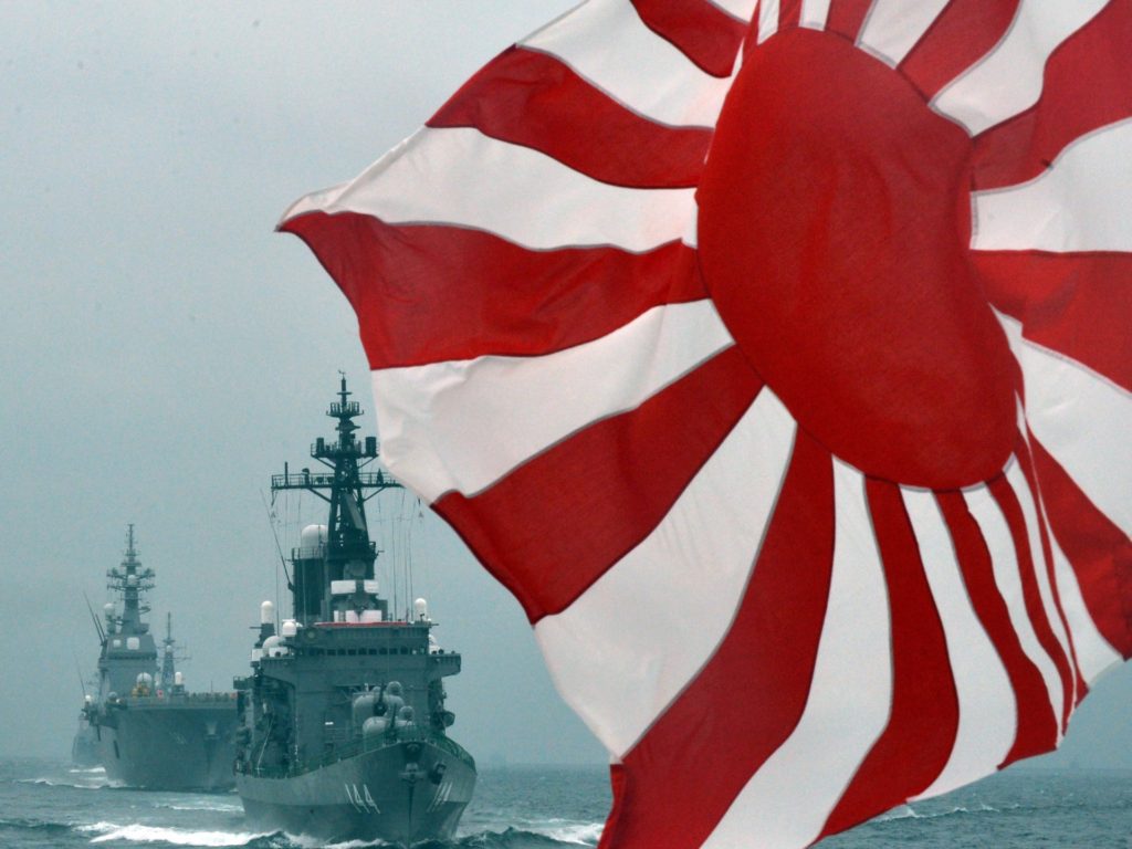 The flag of the Japanese Maritime Self-Defense Force (MSDF) flutters in the wind while MSDF escorts ship Kurama (R) and Hyuga (L) make its fleet review off Sagami Bay, Japan's Kanagawa prefecture on October 14, 2012. AFP PHOTO / KAZUHIRO NOGI (Photo credit should read KAZUHIRO NOGI/AFP/GettyImages)