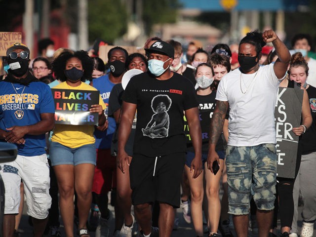 KENOSHA, WISCONSIN - AUGUST 27: Demonstrators protesting the shooting of Jacob Blake march through a neighborhood on August 27, 2020 in Kenosha, Wisconsin. Blake was shot seven times in the back in front of his three children by a police officer. The shooting has led to several days of rioting …