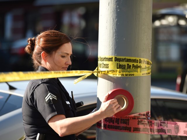A female police officer uses police tape to cordon off an area outside a Jack in the Box r