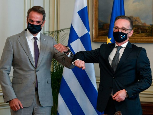 Greek Prime Minister Kyriakos Mitsotakis (L) bumps elbows with Germany's Foreign Minister