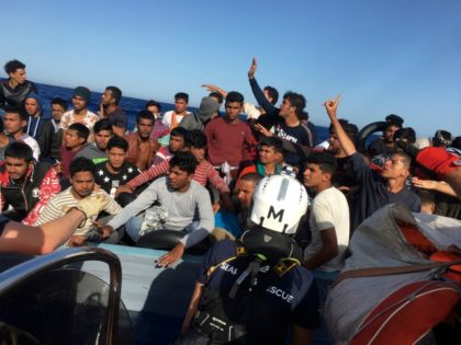 Some of the 67 migrants rescued by members of French NGO SOS Mediterranee boat Ocean Viking off the coast of Lampedusa island react, on June 25, 2020. - Dozens of migrants drifting in the Mediterranean on a blue wooden boat were rescued on June 25, 2020 by activists on a …