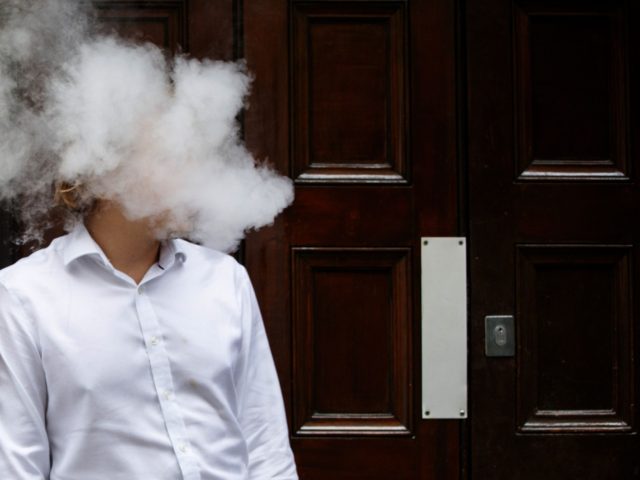 A smoker is engulfed by vapours as he smokes an electronic vaping machine during lunch tim