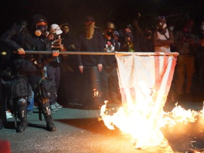 PORTLAND, OR - AUGUST 1: A protester burns an American flag in front of the Mark O. Hatfield U.S. Courthouse in the early morning on August 1, 2020 in Portland, Oregon. Friday was the second night in a row without police intervention, following weeks of clashes between federal officers and …