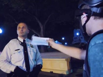 protester waves mask in officer's face