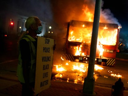 A protester stands near a burning garbage truck outside the Kenosha County Courthouse, late Monday, Aug. 24, 2020, in Kenosha, Wis. Protesters converged on the county courthouse during a second night of clashes after the police shooting of Jacob Blake a day earlier turned Kenosha into the nationâ€™s latest flashpoint …