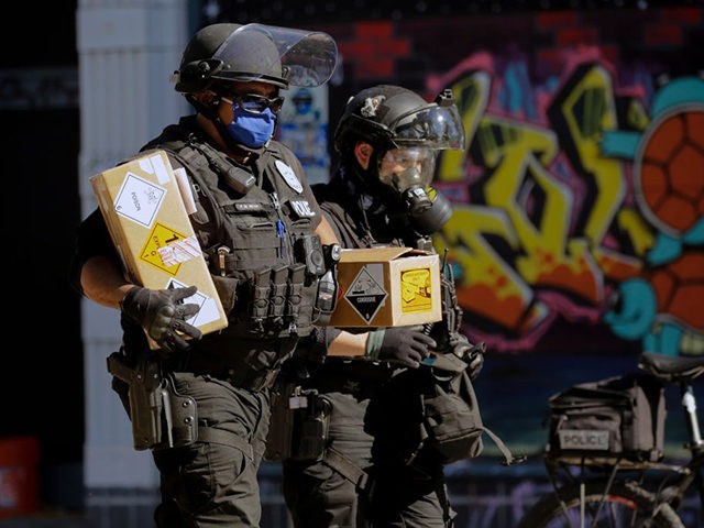 Seattle police officers carry boxes with warning stickers and a slip of paper that reads "blast balls" as police clash with protesters following a "Youth Day of Action and Solidarity with Portland" demonstration in Seattle, Washington on July 25, 2020. - Police in Seattle used flashbang grenades and pepper spray …
