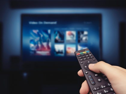 VOD service screen with remote control in hand. Video On Demand television internet stream