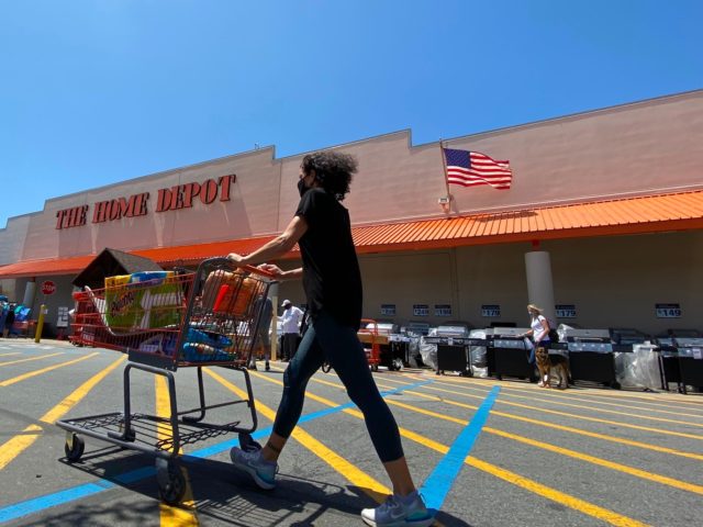 A shopper wearing a facemask pushes her cart while people wait in line to enter The Home Depot in Marina Del Rey, California on May 22, 2020, amid the novel coronavirus pandemic. (Photo by Chris DELMAS / AFP) (Photo by CHRIS DELMAS/AFP via Getty Images)
