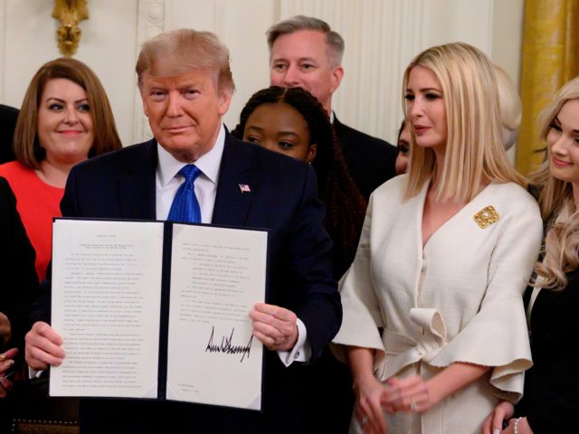 US President Donald holds up an executive order on combating human trafficking next to Iva