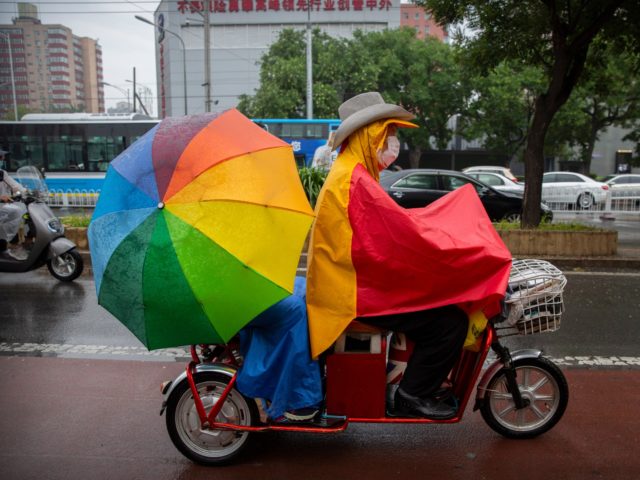 A man wearing a face mask to protect against the spread of the new coronavirus rides a scooter in the rain in Beijing, Thursday, July 9, 2020. (AP Photo/Mark Schiefelbein)