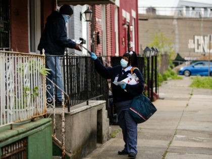 United States Postal Service carrier Henrietta Dixon delivers mail to Alvin Fields in Philadelphia, Wednesday, May 6, 2020. Fields called Dixon "absolutely wonderful." (AP Photo/Matt Rourke)