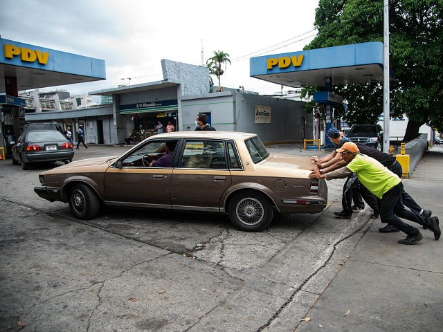 CARACAS, VENEZUELA - JUNE 01: Four men push a car that ran out of gas into a gas station o