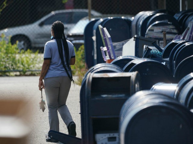 A postal employee walks past mail boxes in the parking lot of a post office in the Borough of the Bronx on August 17, 2020 in New York. - The United States Postal Service is popularly known for delivering mail despite snow, rain or heat, but it faces a new …