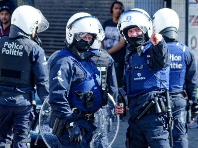 Belgian police officers wearing protective gears stand at the site of unrests in Anderlecht, Brussels, on April 11, 2020. - People gather in a reaction to the death of a 19-year-old young man, who died after his scooter collided with a police car during a chase the night before. (Photo …