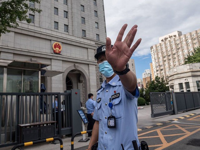 A police officer gestures before an escorted police van carrying Chinese property tycoon R