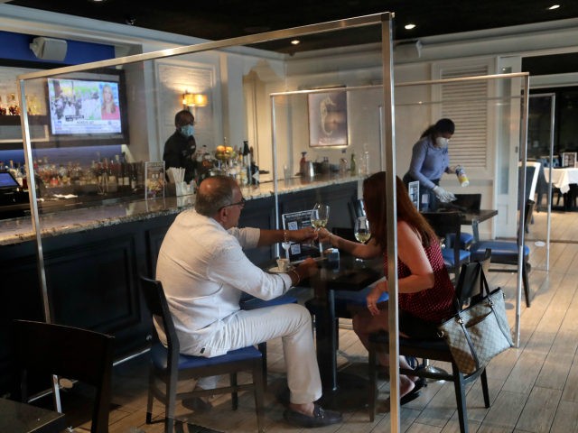 Joseph and Julia Salvaggio, vacationing from Long Island, N.Y., enjoy a glass of wine at the Wild Sea Oyster Bar and Grille at the Riverside Hotel during the new coronavirus pandemic, Tuesday, May 26, 2020, in Fort Lauderdale, Fla. The restaurant closed the bar and installed protective dividers between tables. …