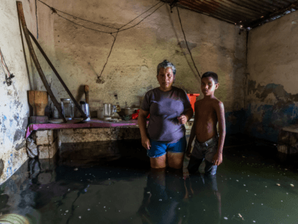 A woman and her son pose inside their flooded house in San Felix, Bolivar state, Venezuela