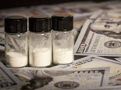Illegal drugs in powder form are surrounded by American $100 bills.