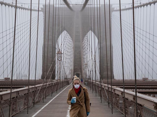 NEW YORK, NY - MARCH 20: A woman wearing a mask walks the Brooklyn Bridge in the midst of the coronavirus (COVID-19) outbreak on March 20, 2020 in New York City. The economic situation in the city continued to decline as New York Gov Andrew Cuomo ordered all nonessential businesses …