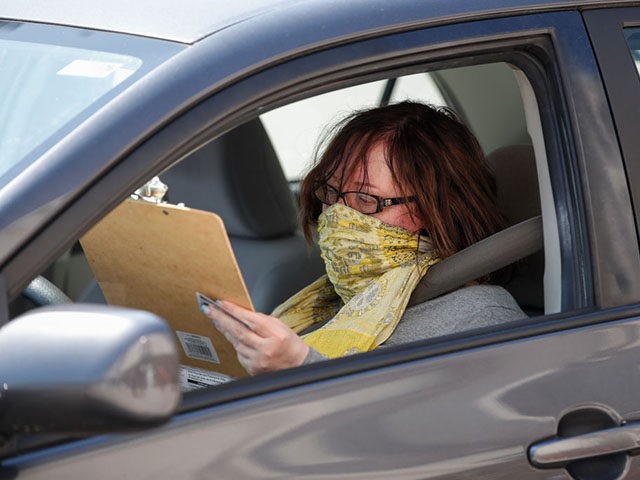 A woman votes from her car in a Democratic presidential primary election at a drive-up polling place set up outside the Hamilton High School in Milwaukee, Wisconsin, on April 7, 2020. - Americans in Wisconsin began casting ballots Tuesday in a controversial presidential primary held despite a state-wide stay-at-home order …