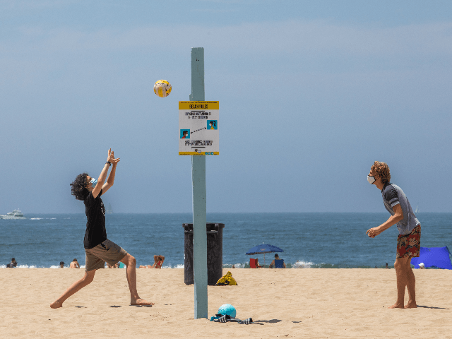 Men wearing face masks play volleyball on the beach amid the severe heat wave in Venice, California on August 15, 2020. - The worst heat wave in several years caused rolling blackouts August 14, 2020 due to power shortages and is setting up dangerous conditions across California. (Photo by Apu …