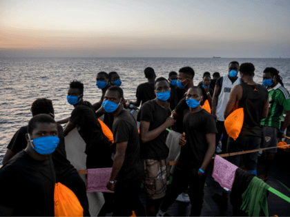 Migrants stand at sunset onboard the Sea-Watch 4 civil sea rescue ship react on sea off the coast of Sicily, Italy, on August 31, 2020. - More than 350 migrants are onboard the Sea-Watch 4, after it took more than 150 people from the German-flagged MV Louise Michel rescue vessel …