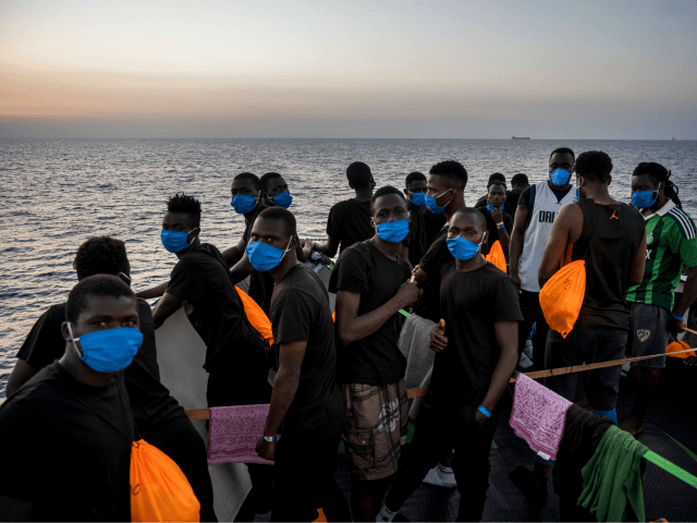 Migrants stand at sunset onboard the Sea-Watch 4 civil sea rescue ship react on sea off th